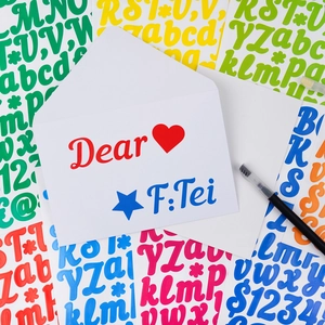 Détail d'autocollants de lettres colorées sur une enveloppe pour journaux DIY et cadeaux