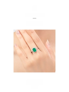 Macro shot of emerald-cut gemstone ring with sparkling diamond halo and silver band