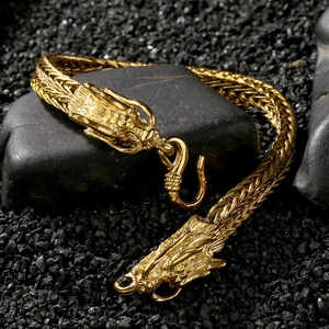Macro shot of gold dragon head bracelet detailing the intricate metal weaving on dark stones