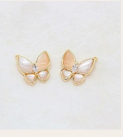 Detail of butterfly earring charms with gold frames and pink shell wings for DIY jewelry