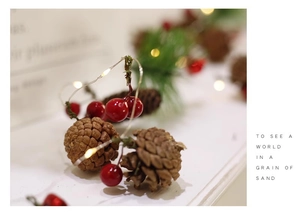 Close-up of LED Christmas string lights with pine cones, red berries and pine needles