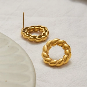 Elegant gold twisted hoop earrings crafted in stainless steel on a soft white fabric background