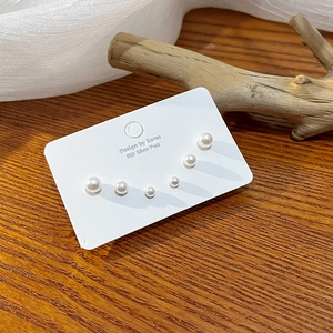 Three pairs of pearl stud earrings set with 925 silver needles on a rustic wooden surface