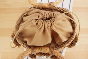 Detail view of handmade woven straw bucket bag with drawstring liner and pearl tassels