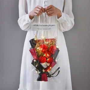 Detail of flower bouquet in a transparent bag with warm LED lights and red carnations