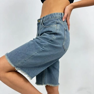 Detail view of denim Bermuda shorts with frayed edges and classic blue wash finish