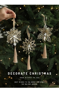 Detailed view of golden snowflake metal ornaments with tassels on a Christmas tree