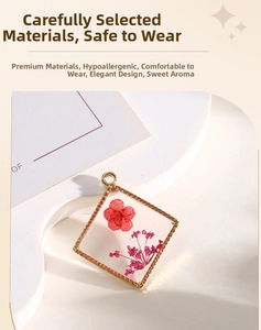 Close-up of square gold pendant with red dried flowers and clear resin detail