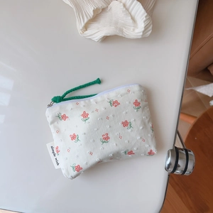 Close-up of floral cotton pouch with 3D polka dot texture and green woven zipper pull