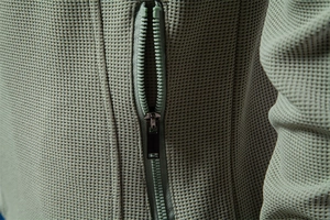 Macro shot of light green jacket featuring breathable waffle texture fabric and premium zipper