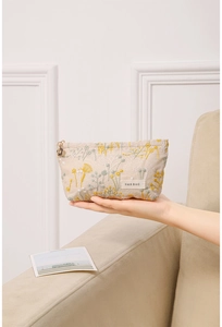 Détail de broderie florale sur trousse en lin avec tirette de fermeture en fleur