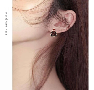 Close-up of a Christmas tree stud earring with red gemstone dots on a female model