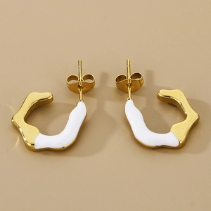 Detail of C-shaped geometric earrings with gold finish and white enamel drip