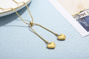Detail of golden snake chain necklace with heart pendants and adjustable slider