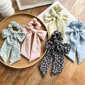 Flat lay of colorful floral scrunchies with long ribbons on a rustic wooden table