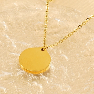 Close-up of a gold-toned titanium steel evil eye pendant necklace on a textured background