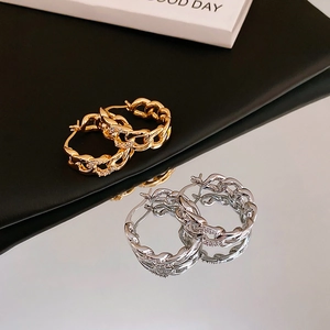Detailed view of intertwined gold and silver link earrings with zircon stone accents
