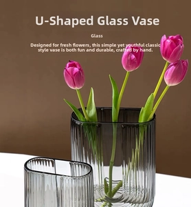 Macro detail of U-shaped smoke grey glass vase with vertical stripes and pink tulips