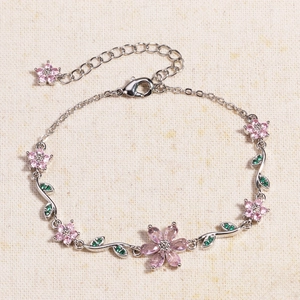 Close-up of pink zircon flowers and green marquise gems on a silver chain bracelet