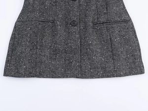 Detail of grey herringbone tweed fabric with black round buttons and pocket design
