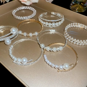 Close-up of layered pearl bracelets with sparkling rhinestones on a golden display tray