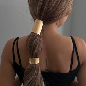 Luxurious gold geometric metal hair rings for ponytails on model against grey wall