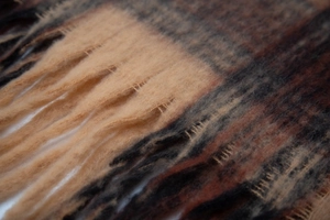 Detailed macro view of the thick plush checkered scarf featuring tassels and soft texture