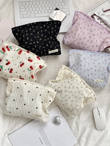 Trousses de toilette à fleurs en toile plissée de plusieurs couleurs sur un fond de lit