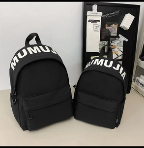 Detail view of two black nylon backpacks in large and small sizes with white lettering