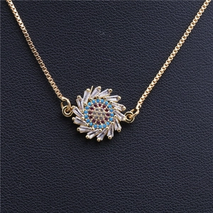 Macro shot of gold-plated sunburst pendant with zircon stones and blue-red gem details