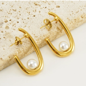 Macro view of minimalist golden U-shaped earrings featuring a round white pearl on stone