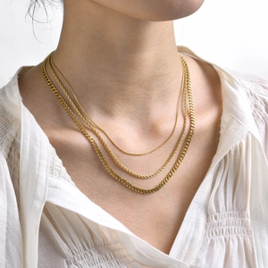Golden 3-piece layered necklace set with snake, twisted, and cuban chains on model