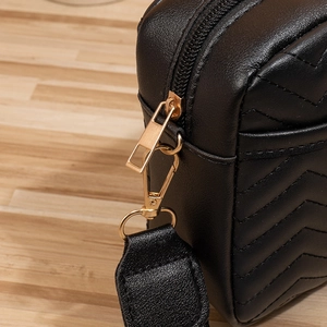 Close-up of golden hardware and chevron quilted pattern on black leather shoulder bag
