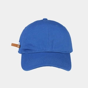 Close-up of royal blue cotton baseball cap with brown leather label and woven tag detail