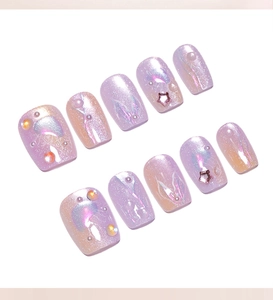Detail of purple cat-eye press-on nails with 3D pearls and pink star sequins