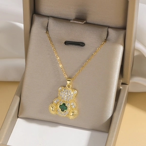 Golden bear necklace with green clover and sparkling zircon on satin fabric