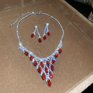 Detail of silver jewelry set with red oval gemstones and diamonds on a brown display tray