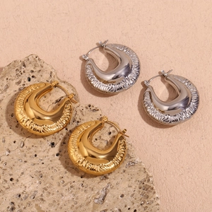 Detailed view of textured chunky C-shaped hoop earrings in gold and silver finish