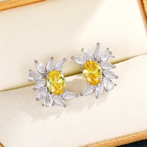 Sparkling flower-shaped stud earrings with yellow oval zircon and silver base in a box