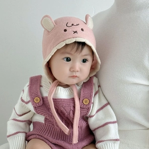 Close-up of pink baby knitted hat with animal ears and matching striped romper detail