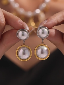 Detail of elegant two-tone gold and silver earrings featuring glossy white pearls