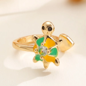 Macro shot of adjustable gold turtle ring with green enamel and clear zircon stone
