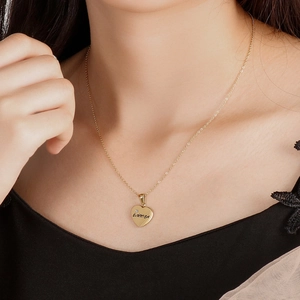 Golden heart pendant necklace with Erica engraving on a thin chain worn by a model