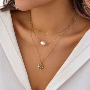 Detailed close-up of layered gold necklace set with faux pearls and blue gemstone pendants