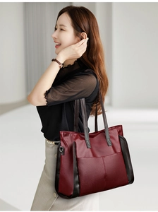 Close-up of a large burgundy tote bag in soft leather texture worn by a model