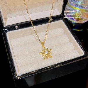 Detail of gold starburst compass pendant with sparkling zircons in a jewelry box