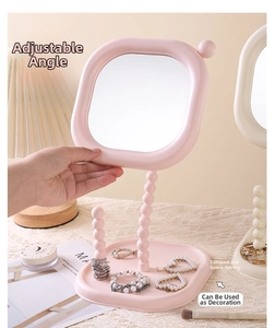 Close-up of pink cream rotatable makeup mirror with beaded stem and jewelry tray base