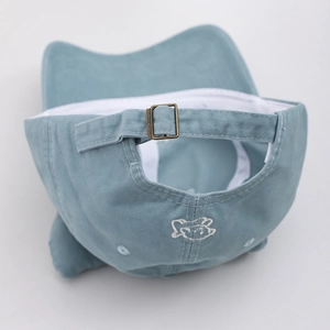 Detail of light blue cotton cap with cat embroidery and adjustable bronze metal buckle