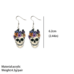 Close-up of acrylic Halloween skull earrings with flower and butterfly patterns