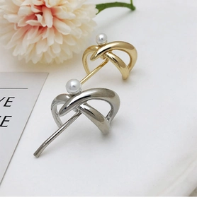 Close-up of elegant gold and silver twisted hair clips with white pearls